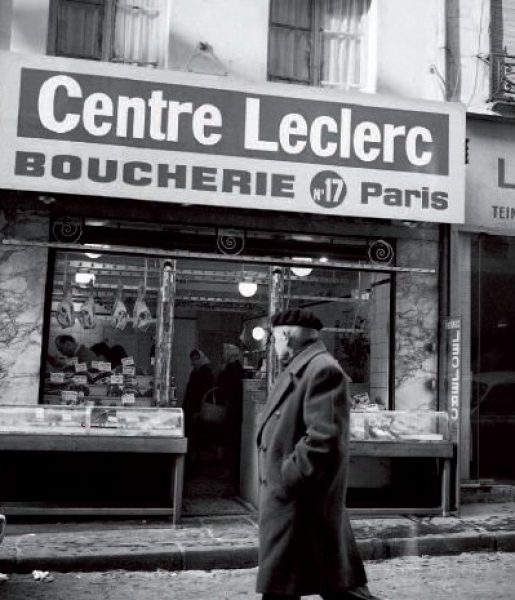 Passant devant une boucherie Centre Leclerc Paris 1963 – @Raymond Depardon /TAM/ECPAD/Défense/PAR 268-4